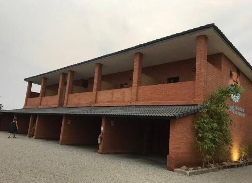 een rood bakstenen gebouw met een vrouw ervoor bij HÔTEL Assinie LODGE in Assinie