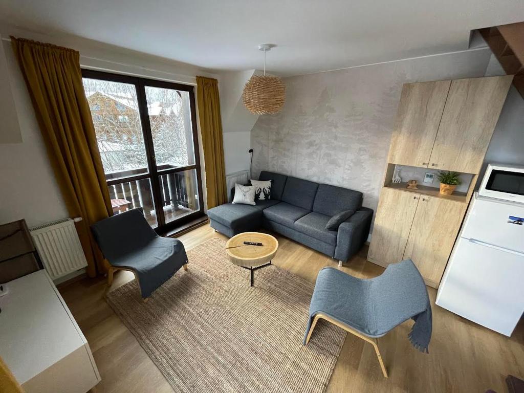 ein Wohnzimmer mit Sofa und Stühlen und eine Küche in der Unterkunft Apartment Stella in Tatranská Lomnica