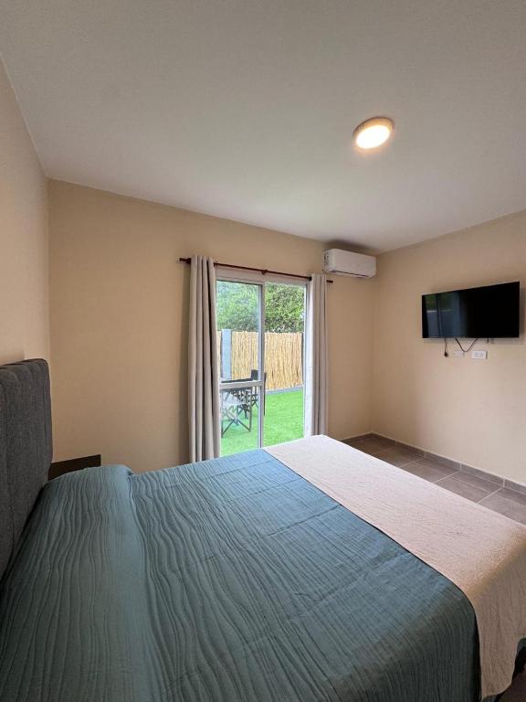 ein Schlafzimmer mit einem großen Bett und einer Glasschiebetür in der Unterkunft Las Moradas Ale in Villa Carlos Paz
