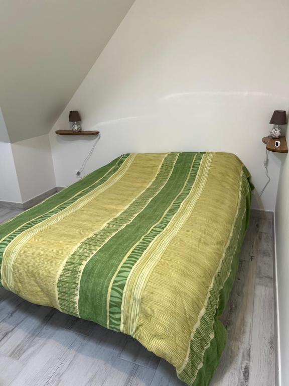 a bed with a green and yellow blanket on it at Reinettes - 2 in Mulsanne