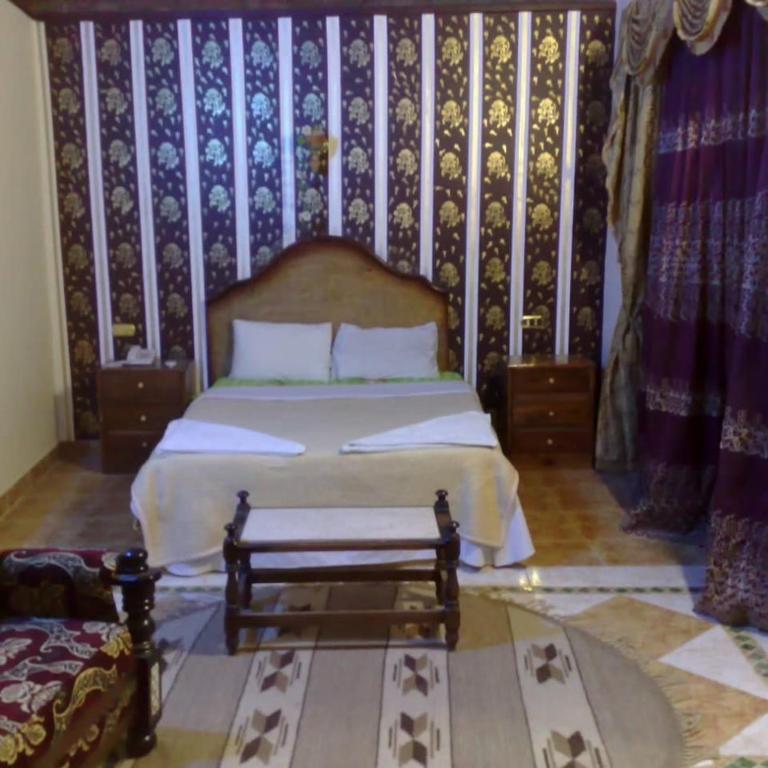 a bedroom with a bed with a wooden headboard at Old Oasis Hotel for Safari Trips in Az Zabū