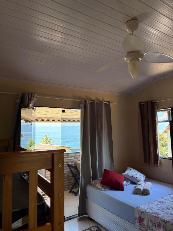 a bedroom with a bed and a ceiling fan at Suítes Carla e Carol in Praia de Araçatiba