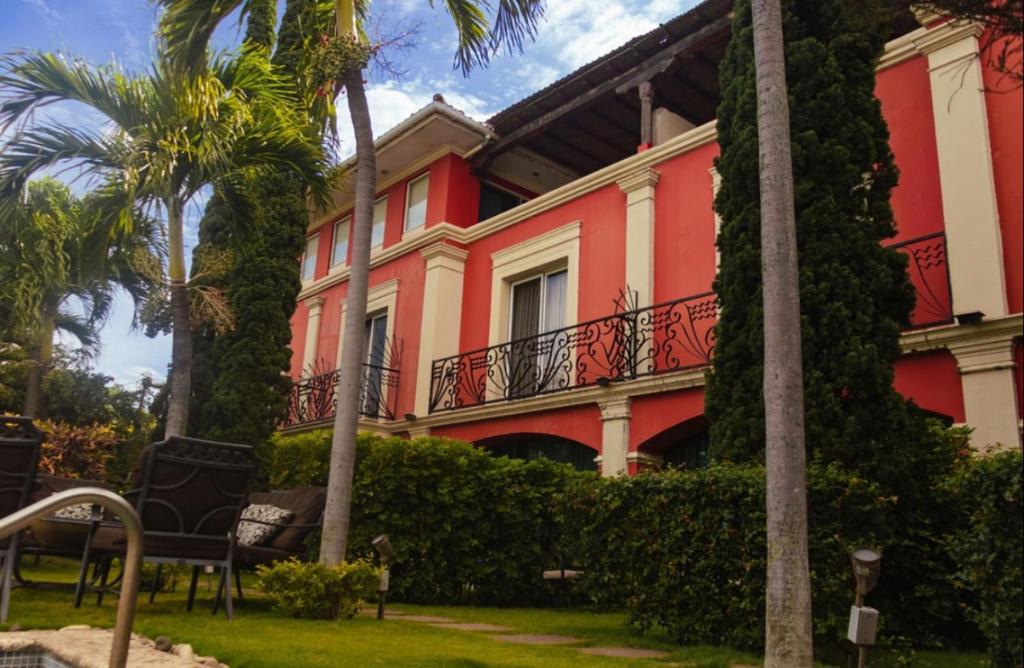 a red building with a balcony and palm trees at Altos de Fontana by Macondo Collection in Managua