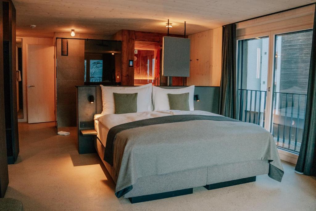 a bedroom with a large bed and a balcony at Roggenstock Lodge in Oberiberg