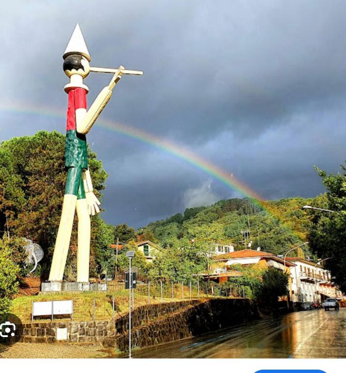 a rainbow in the sky with a statue at La Fatina appartamento in Collodi