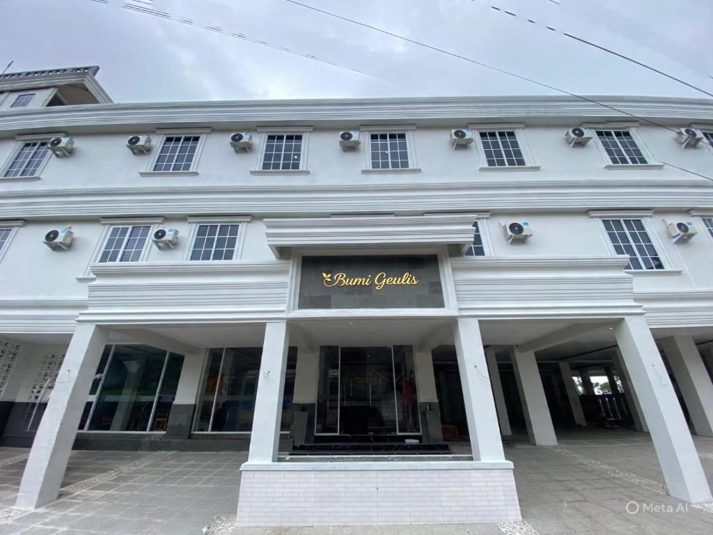 een wit gebouw met een bord erop bij Bumi Geulis Hotel & Residence in Sukabumi