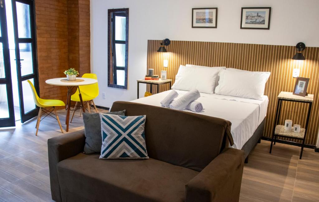 een slaapkamer met een bed, een stoel en een tafel bij Studio Petrópolis - Centro Histórico com Garagem in Petrópolis