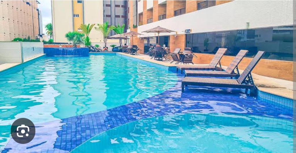 a swimming pool with two chairs in a building at Nomar VI - Gold Flat in João Pessoa