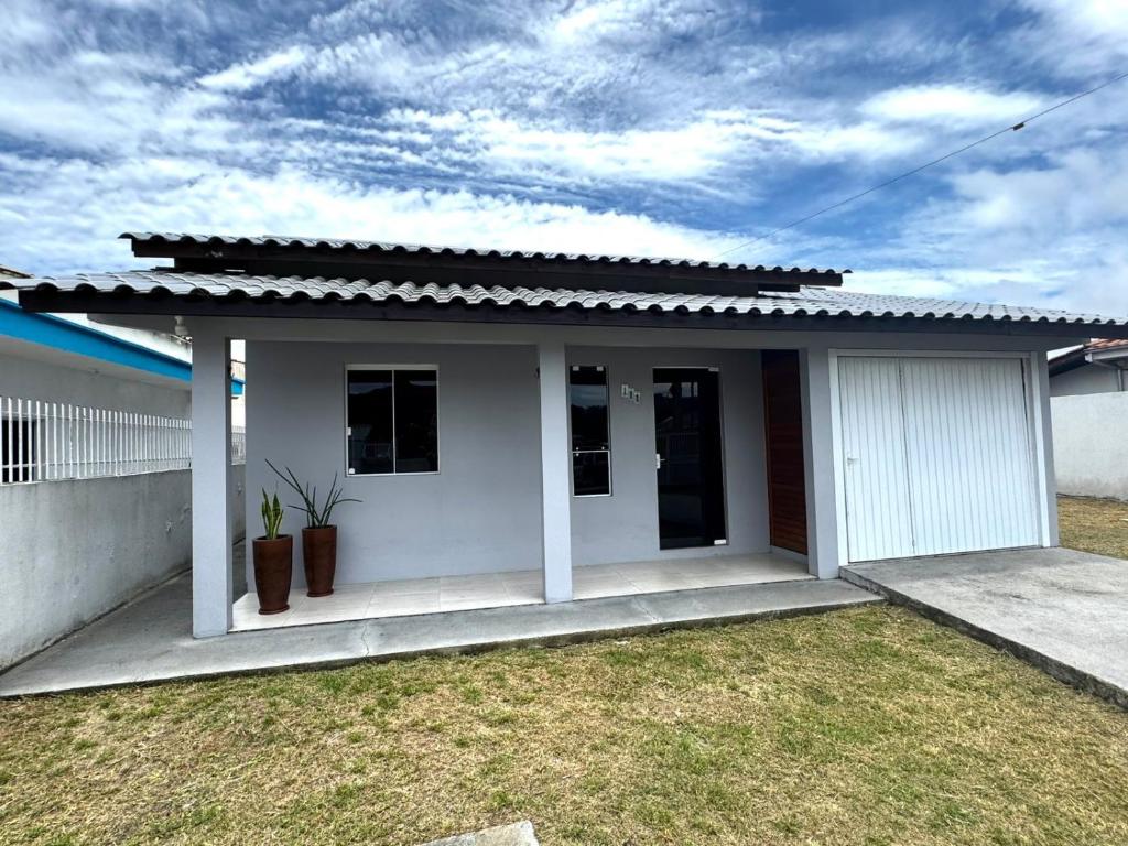 a small white house with a grass yard at Casa em Imbituba SC, perto das Praias e Lagoa in Imbituba