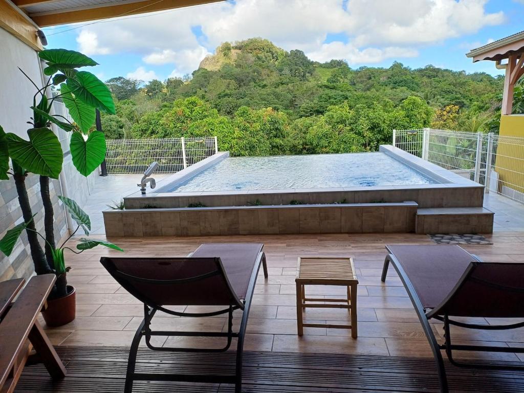 a patio with a pool and chairs and a table at Le Refuge de Nicolas in Quartier Morne Acajou