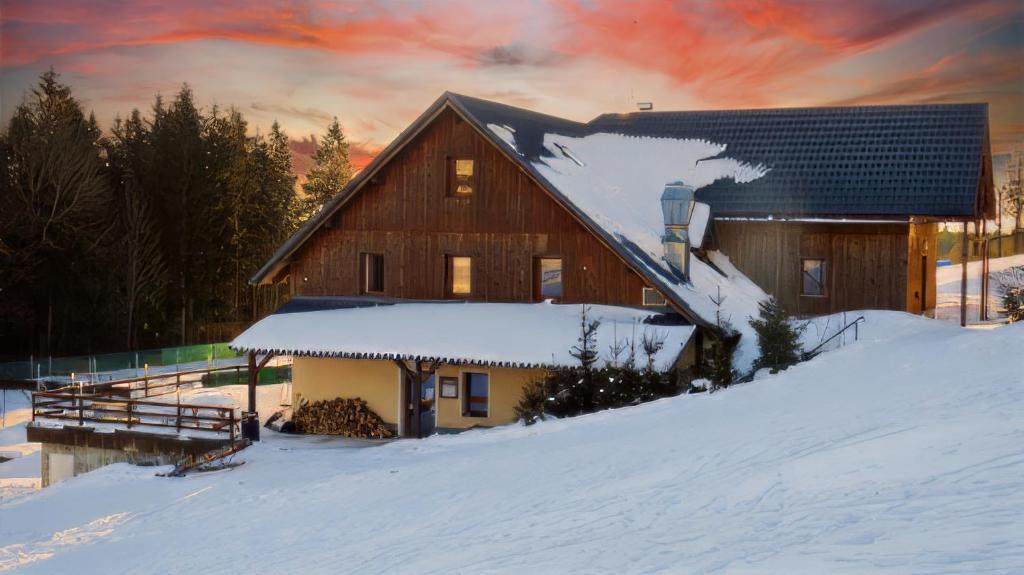 un fienile nella neve con un tramonto di Penzion Čekanka a Strážné