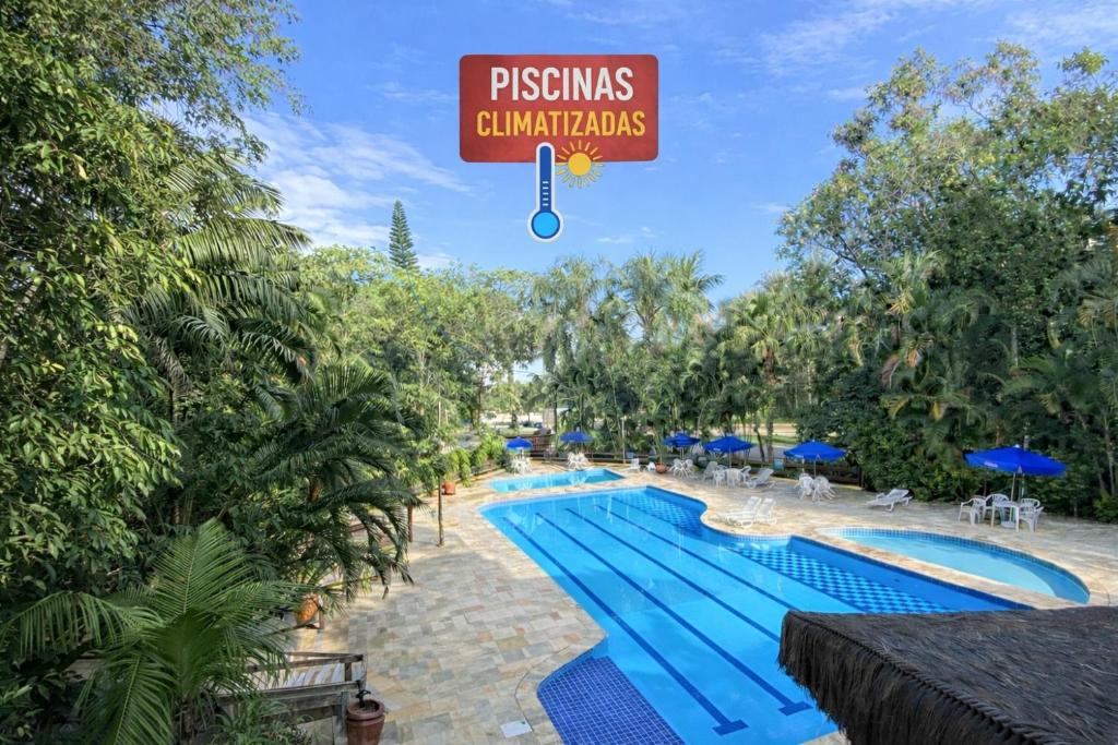 een zwembad in een resort met een bord erboven bij Fabuloso flat 243 Amarílis 2 piscinas climatizadas, carregador veiculo elétrico Riviera de São Lourenço, Bertioga Apartamento Duplex inteiro, cozinha equipada completa, serviço de praia, limpeza e trocas diária de toalhas, wi-fi 500mb in Riviera de São Lourenço