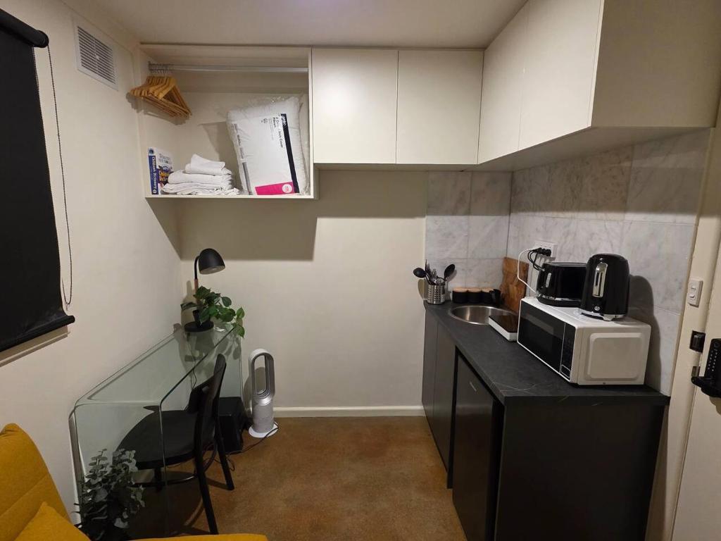 a small kitchen with a counter and a microwave at A Sweet Studio for One in Altona