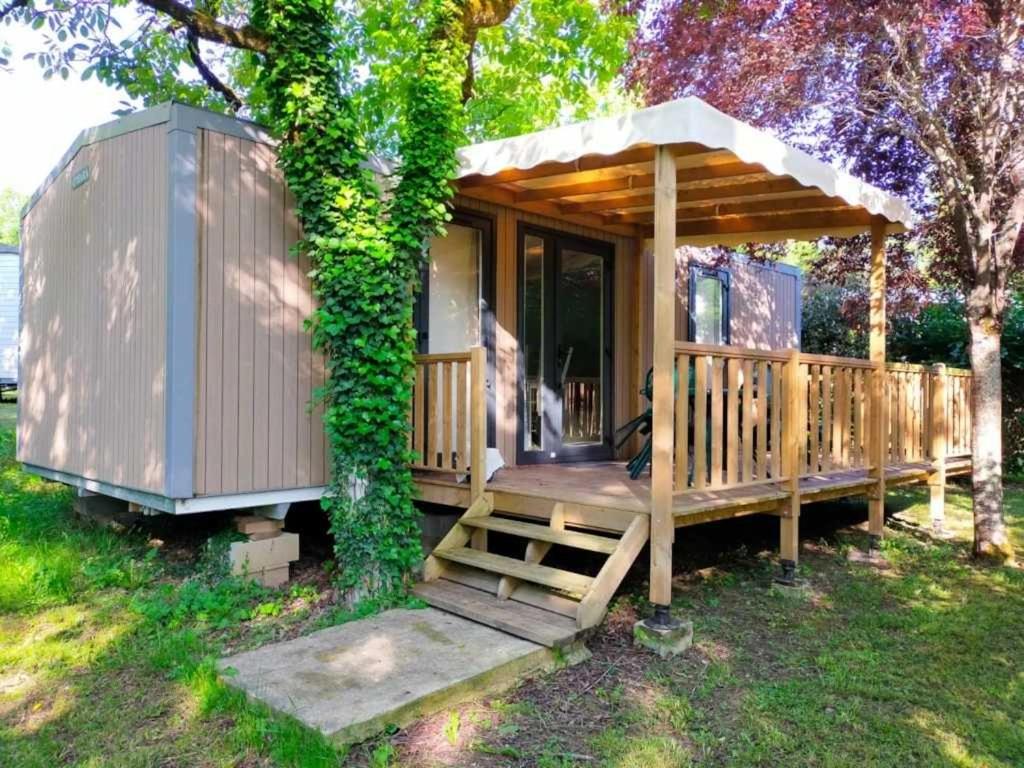 een kleine hut met een houten veranda en een boom bij Camping 4 étoiles - Piscine - ccaaagh in Carennac