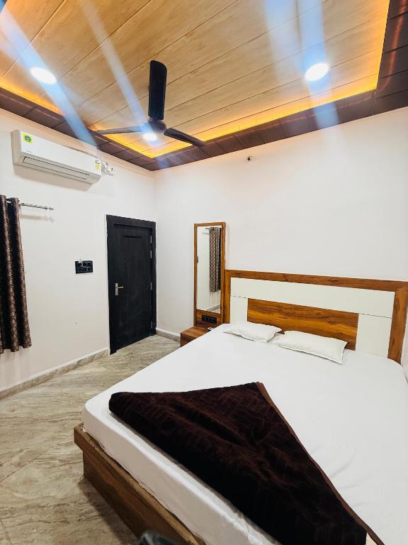 a bedroom with a white bed with a wooden ceiling at Hotel Tathastu Inn in Ujjain