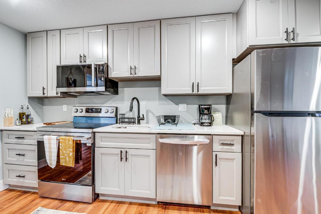 eine Küche mit weißen Schränken und einem Edelstahlkühlschrank in der Unterkunft 4 Blocks to Riverwalk Updated Astoria Studio in Tongue Point Village