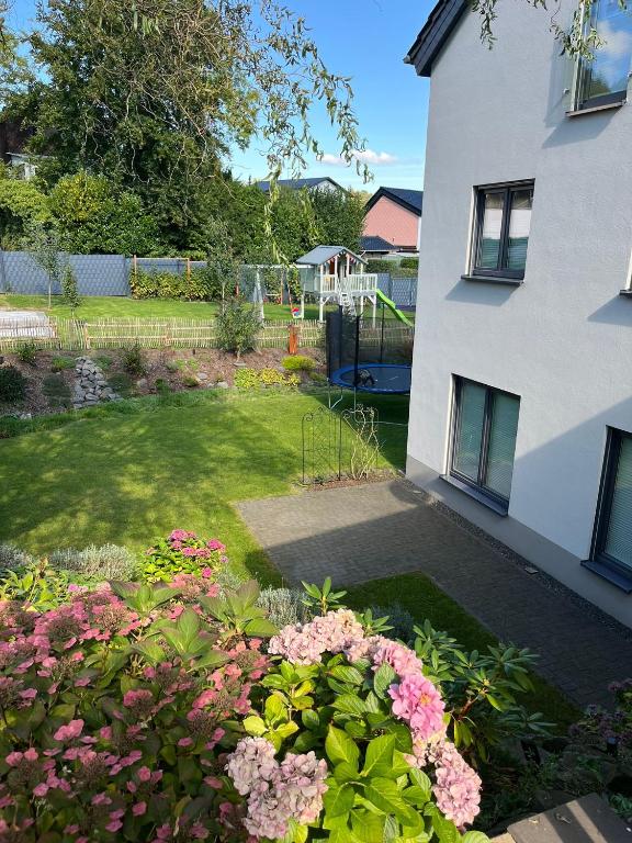 a garden with pink flowers in front of a building at Auszeit am Maar - Ferienwohnung in Schalkenmehren