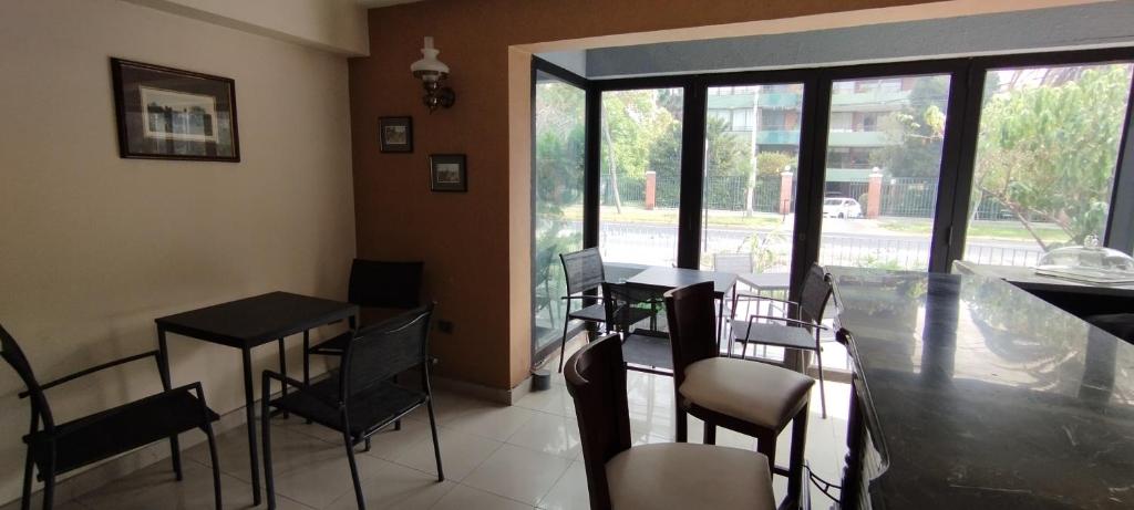 een eetkamer met een tafel, stoelen en ramen bij Hotel Thayer in Santiago