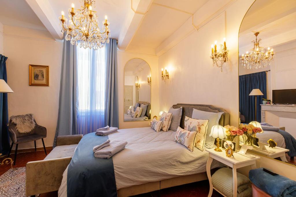a bedroom with a large bed and a chandelier at L'escalier gaucher in Lambesc