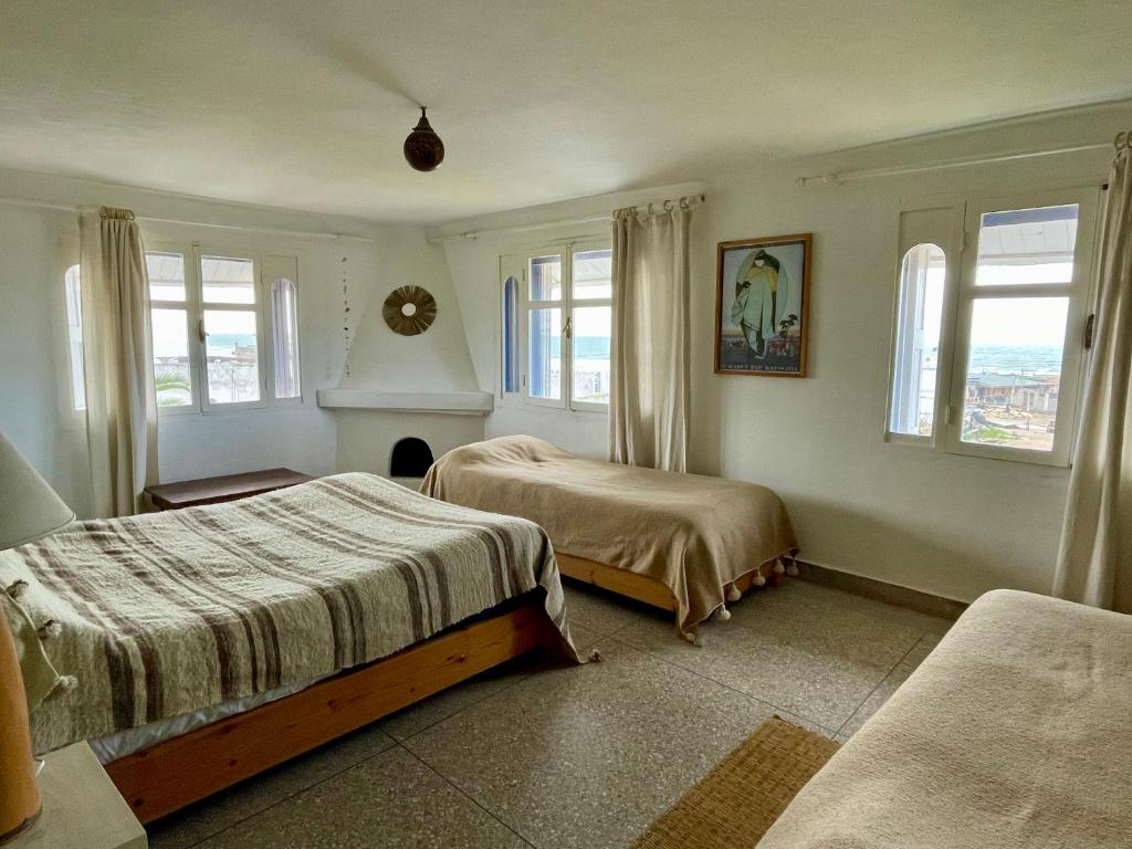 een slaapkamer met twee bedden en twee ramen bij Auberge De La Plage in Sidi Kaouki