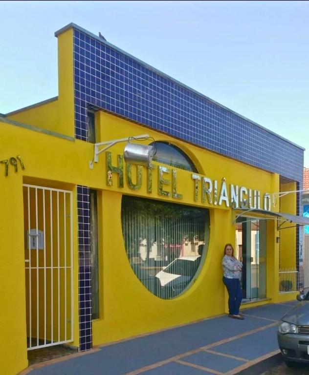 a woman standing in front of a yellow building at Hotel Triangulo Itai in Itaí