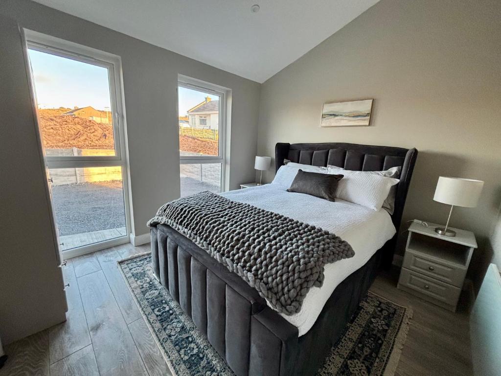 een slaapkamer met een groot bed en een groot raam bij Beyond The Waters Edge Chalet in Dooagh