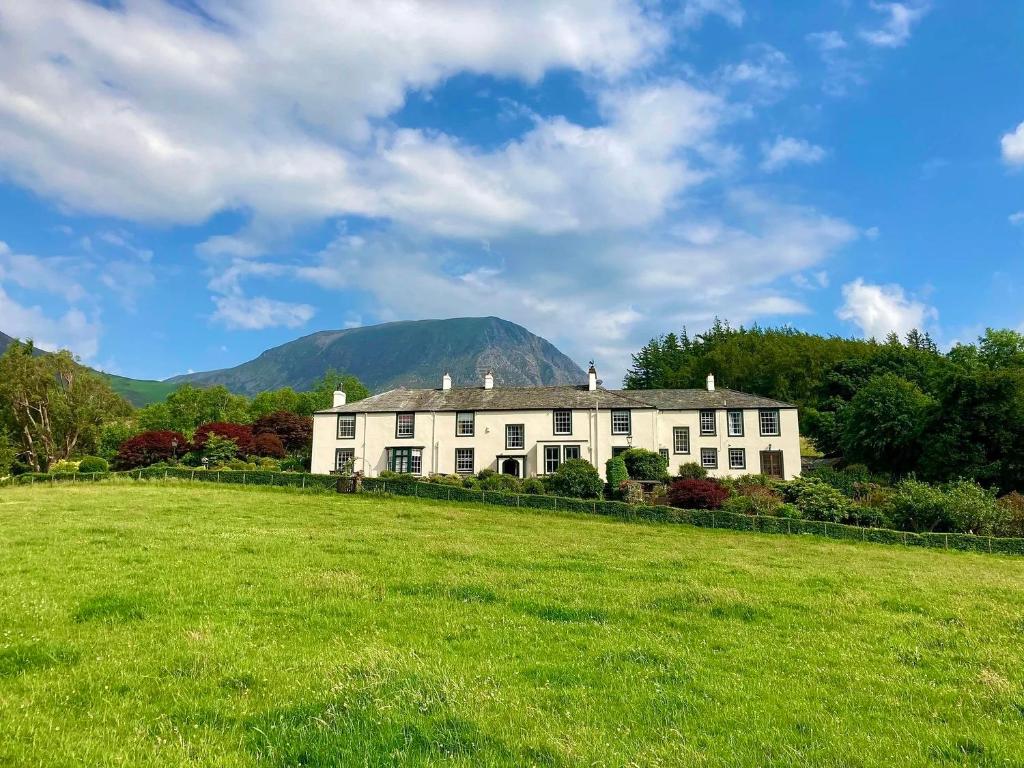 ein Haus auf einem Feld mit Bergen im Hintergrund in der Unterkunft Scale Hill Hotel in Loweswater