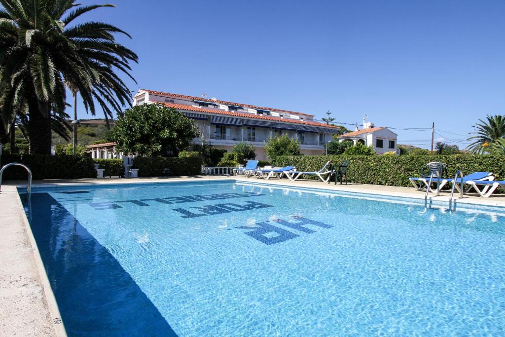 a large blue swimming pool in front of a building at Hostal Port Fornells in Fornells