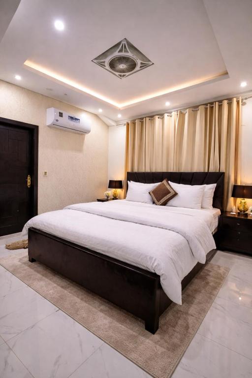 a large bedroom with a large bed with white sheets at LMY Residency - Bahria Town Lahore in Lahore