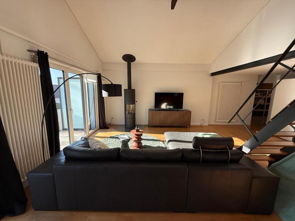 een woonkamer met een zwarte bank en een tv bij LaVida Star Alpine Hideaway Thun, Sauna, free parking in Blumenstein