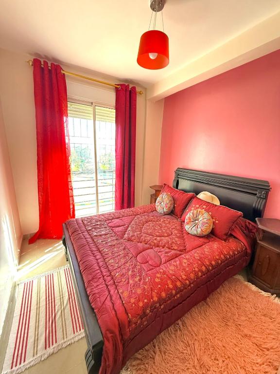 een slaapkamer met een bed met rode lakens en een raam bij Face à la Mer TANGER in Hauara