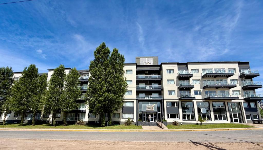 un grande edificio bianco con alberi di fronte di Rincón del Sol - Suite 09 a Pinamar