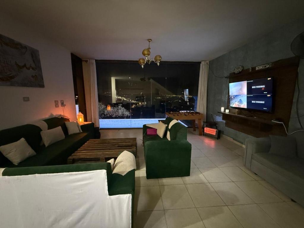 een woonkamer met banken en een flatscreen-tv bij Lion's Den Chaletاستراحة وشاليه في جرش in Jerash