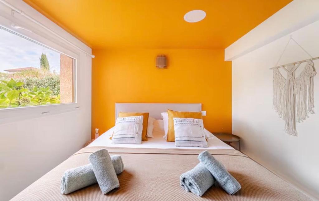 een slaapkamer met gele muren en een bed met 2 kussens bij Studio Wellness & Détente Cosy in Maubec