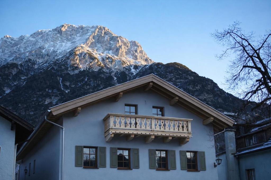 ein Haus mit einem Balkon und einem Berg im Hintergrund in der Unterkunft Karls Design Apartments Mittenwald in Mittenwald