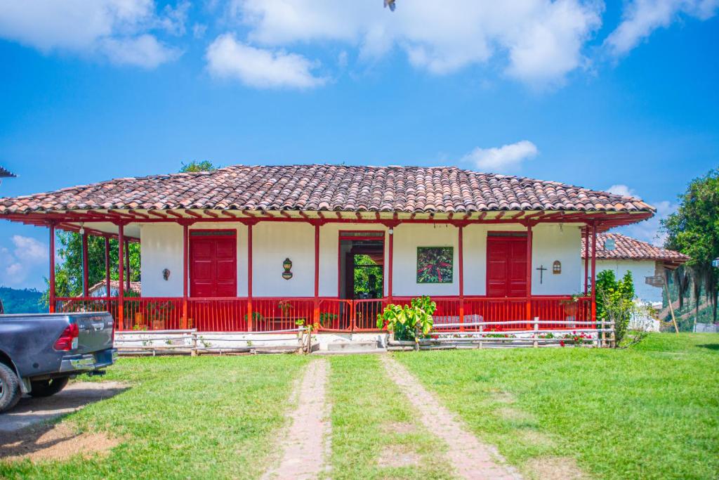 una casa rossa e bianca con una macchina parcheggiata di fronte di Hacienda Santa Bárbara Coffee Farm a La Linda
