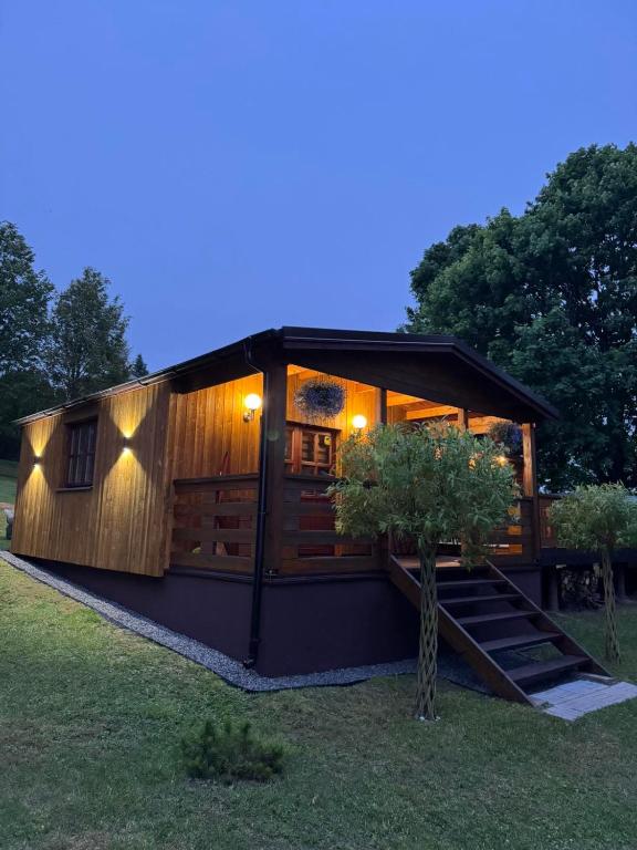 a large wooden cabin with a tree in the yard at Pasakų namelis in Svėdasai