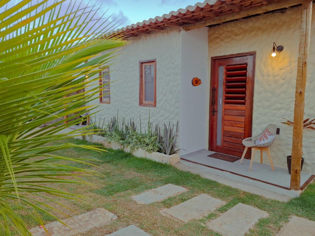 une petite maison avec une porte rouge et une chaise dans l'établissement Wind Village Icaraizinho, à Icaraí