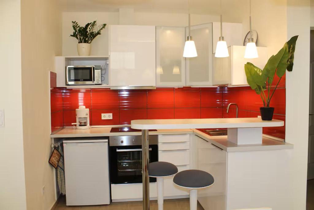 a kitchen with white cabinets and red tiles at City Centre Apartment in Budapest