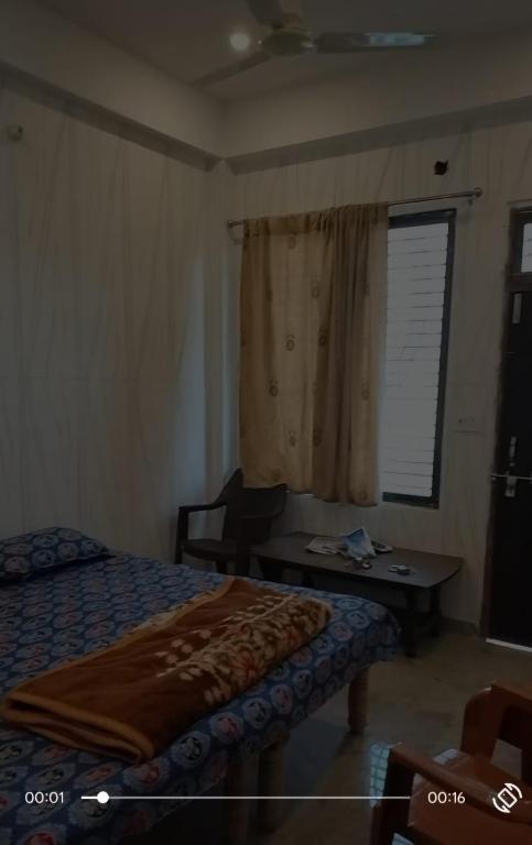 a bedroom with a bed and a desk and a window at Siddhi's Inn in Prayagraj