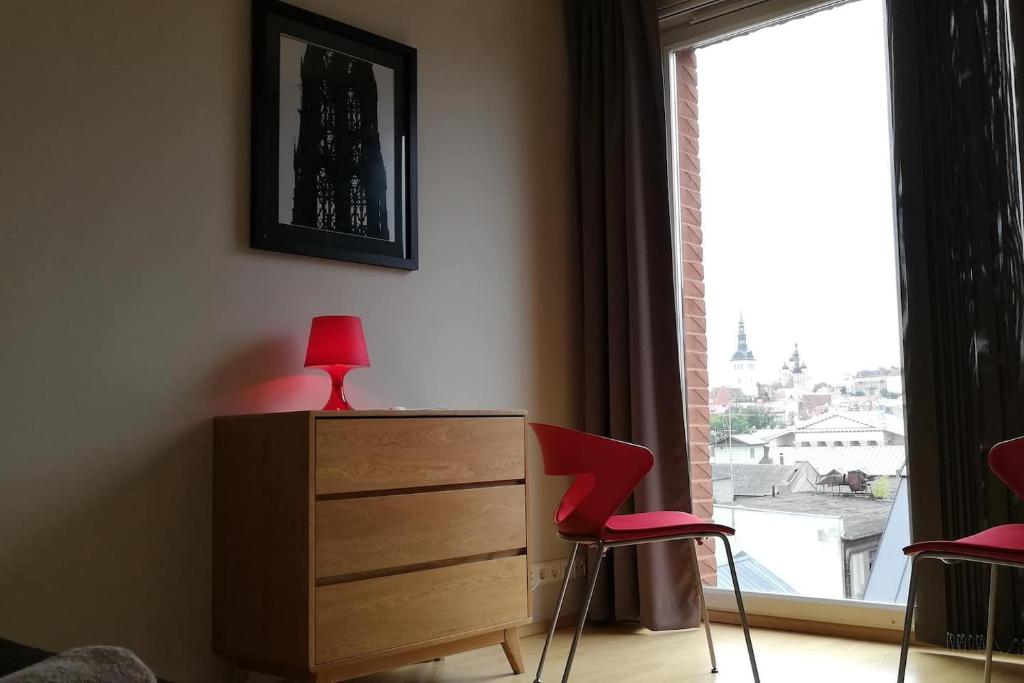 a bedroom with a dresser and two red chairs and a window at Studio Deluxe in Tallinn