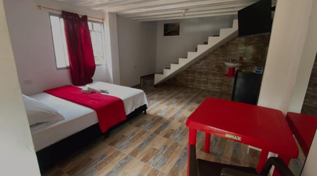 a bedroom with a bed with a red blanket and a staircase at Finca Hotel Yamboró in Pitalito