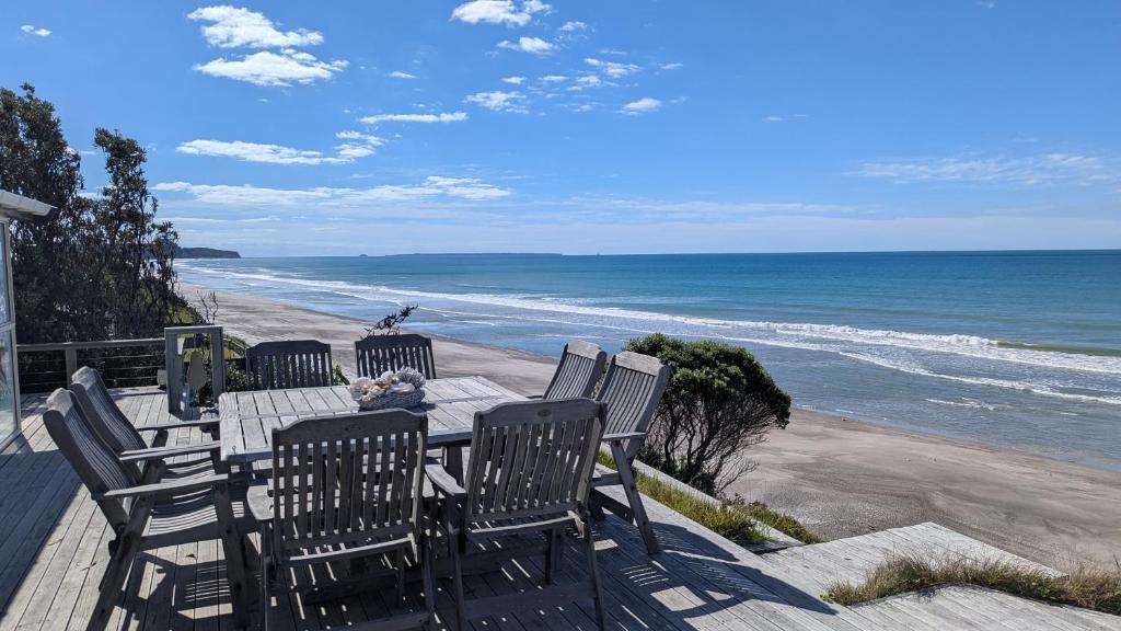 a wooden table and chairs on the beach at Gorgeous Beach House in Pukehina