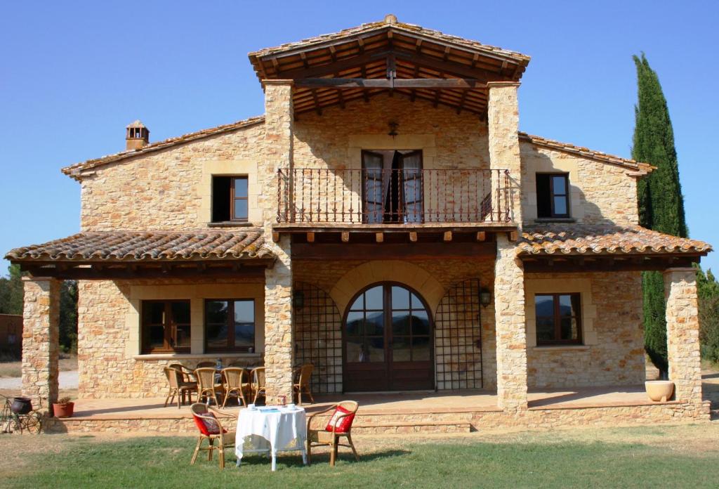 uma vista exterior para uma casa de pedra com uma mesa e cadeiras em Mas Saris em Peratallada