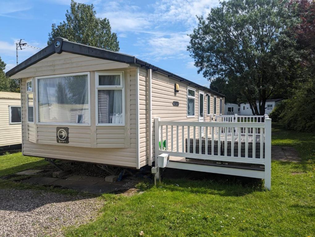 a small house with a white fence in a yard at Denny's Holiday Homes in Blackpool