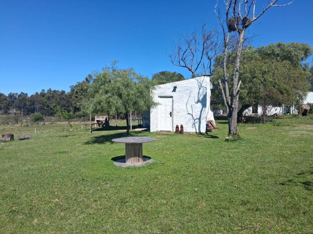 eine weiße Scheune mit einem Tisch im Gras in der Unterkunft Casita de Campo - Chacra Lavanda in Salto