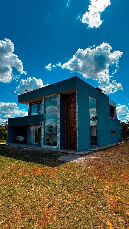 a house with a blue facade on a grass field at Casa Bela Vista do Cerrado in Samambaia