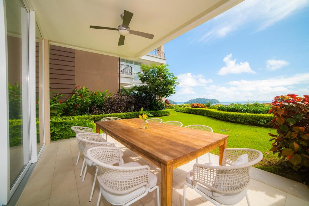 eine Terrasse mit einem Holztisch und weißen Stühlen in der Unterkunft Montecielo 3E 3bdrs ocean view in Los Suenos in Herradura