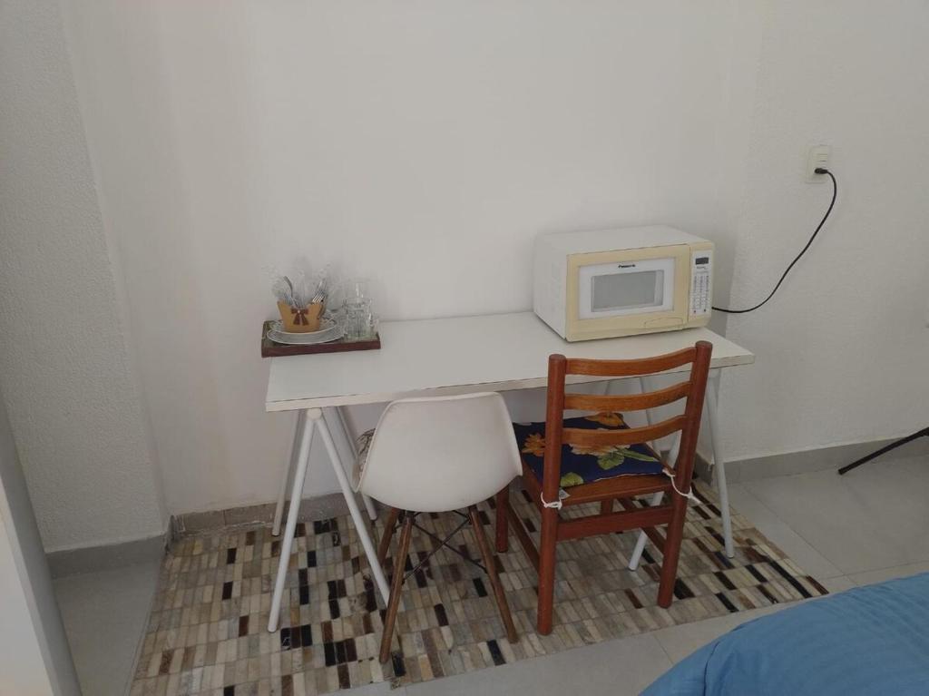 a white desk with a microwave and a chair at Suite 1 com Ar-Condicionado, TV, Wi-Fi e Geladeira in Jundiaí