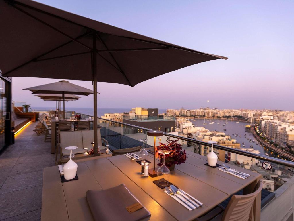 un balcone con tavolo e ombrellone di Mercure St. Julian's Malta a San Giuliano